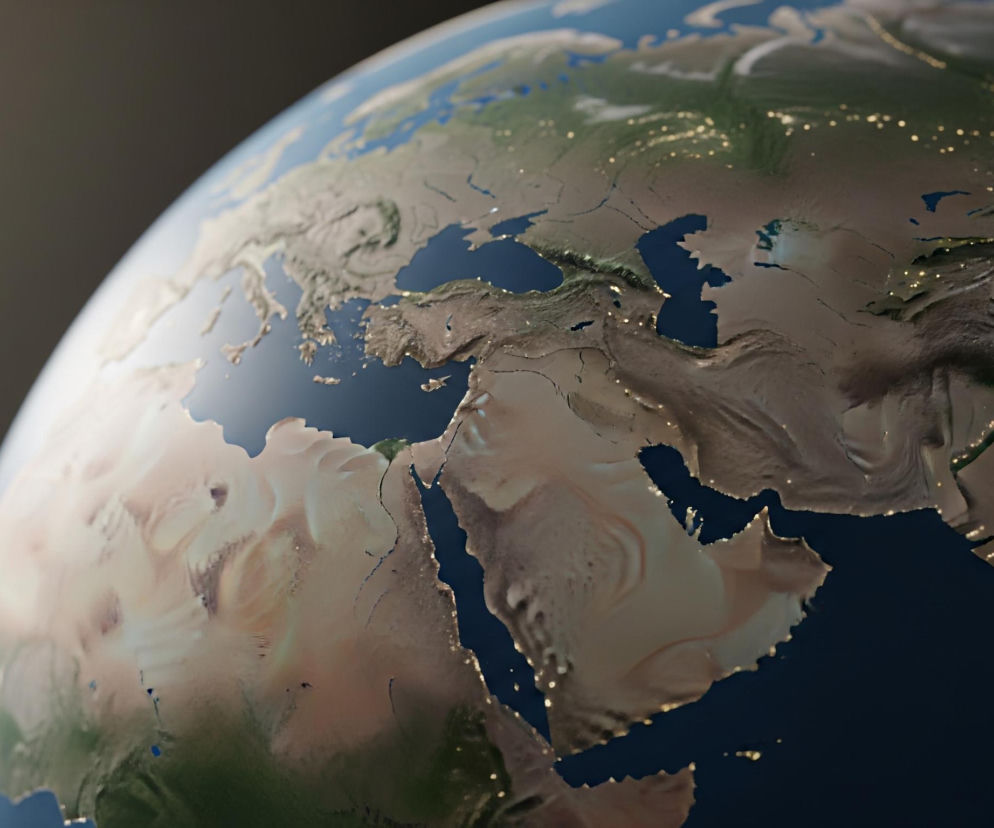 Fragment Ziemi z kosmosu, ukazując jej zakrzywioną powierzchnię z widocznymi kontynentami i oceanami. Dominują tu odcienie brązu, beżu i zieleni na lądach oraz intensywnego błękitu na wodach, z licznymi jasnymi punktami symbolizującymi światła miast na obszarach lądowych. Lewa strona globu jest jaśniej oświetlona, co sugeruje wschód słońca lub intensywne światło padające z lewej górnej części kadru, podczas gdy prawa strona kontynentów jest pogrążona w ciemności, z wyraźnie widocznymi, rozproszonymi skupiskami świateł. Tło zdjęcia jest jednolicie ciemne, prawie czarne, z delikatnym rozmyciem, co podkreśla skupienie na planecie.