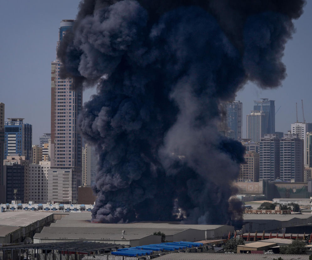 Gęsty, ciemny dym unosi się nad niższym budynkiem w Dubaju na tle wysokich wieżowców, co nawiązuje do informacji o ataku Iranu na Zjednoczone Emiraty Arabskie. Więcej na ten temat przeczytasz na portalu Super Biznes.