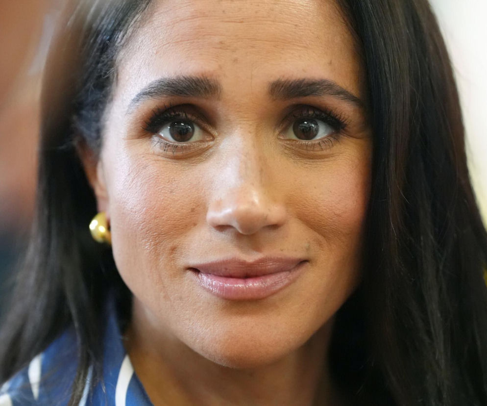 Portret uśmiechniętej Meghan Markle w złotych kolczykach. O jej życiowej metamorfozie przeczytasz na SE.