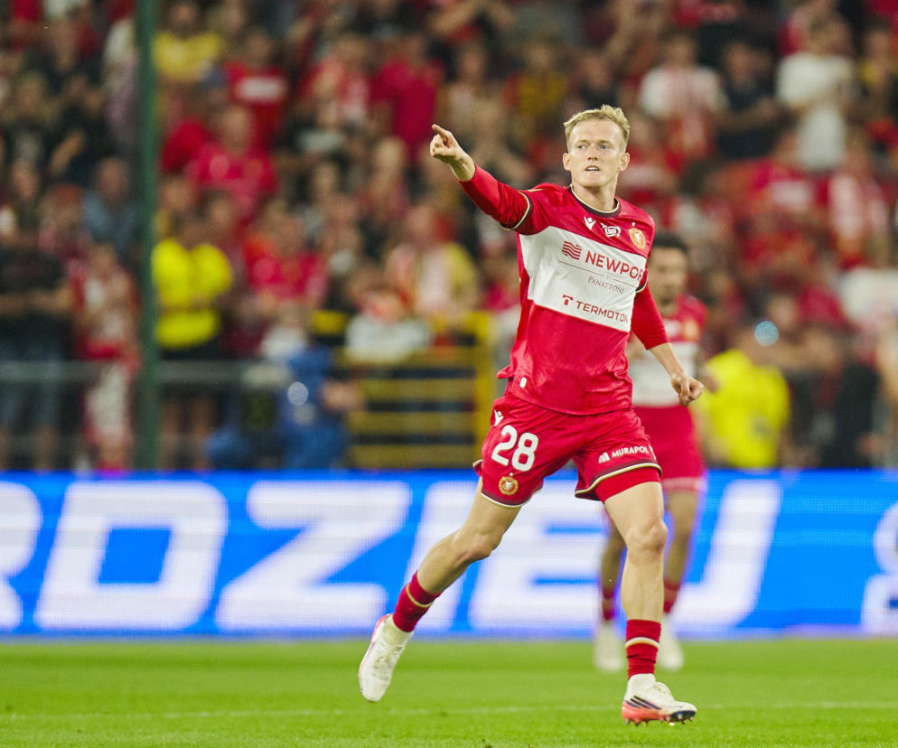 Karol Świderski w czerwonym stroju Widzewa Łódź wskazuje palcem na boisku. O meczu z Lechem przeczytasz na SE Supersport.