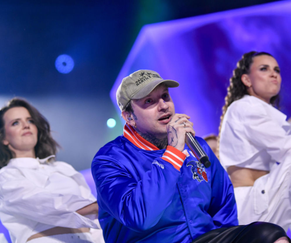 Smolasty w niebieskiej kurtce i beżowej czapce śpiewa do mikrofonu. O nowej płycie artysty przeczytasz na Eska.