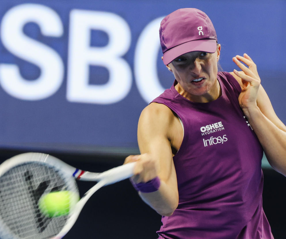 Iga Świątek w fioletowym stroju odbija piłkę rakietą podczas meczu. O turnieju WTA w Wuhan przeczytasz na SE Supersport.