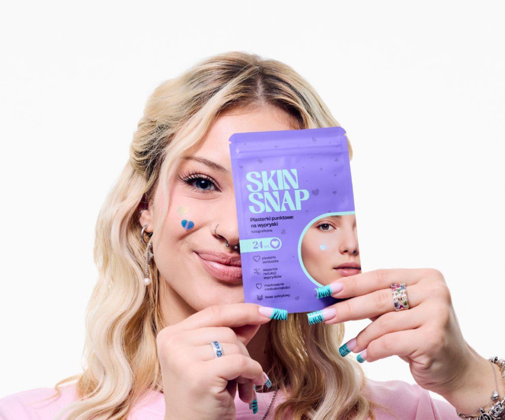 Uśmiechnięta blondynka z kolorowymi plasterkami na policzku trzyma opakowanie Skin Snap. O pielęgnacji cery przeczytasz na Eska.