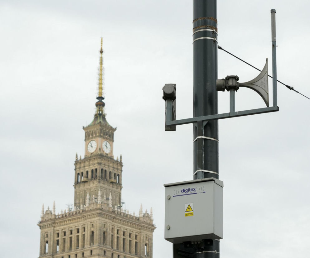 Syrena alarmowa na słupie na tle Pałacu Kultury i Nauki. O testach systemu w Warszawie przeczytasz na SE.
