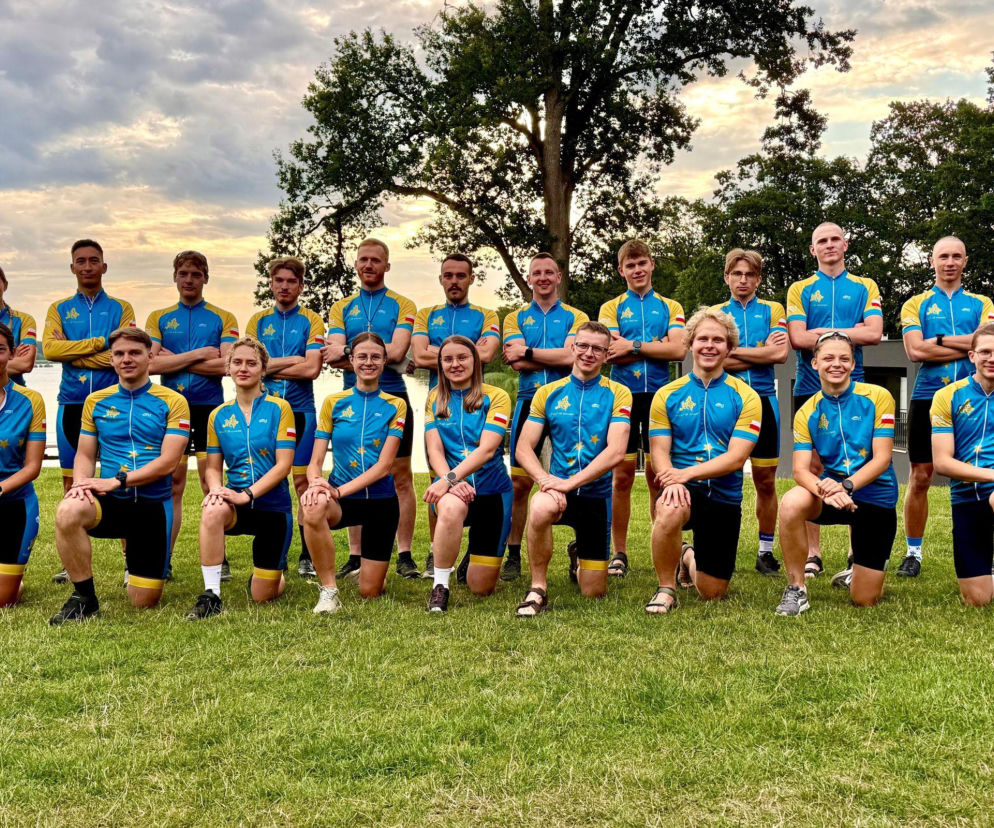 Grupa rowerzystów Niniwa Team pozuje nad wodą przed wyprawą na Korsykę. O szczegółach przeczytasz na Radioplus.