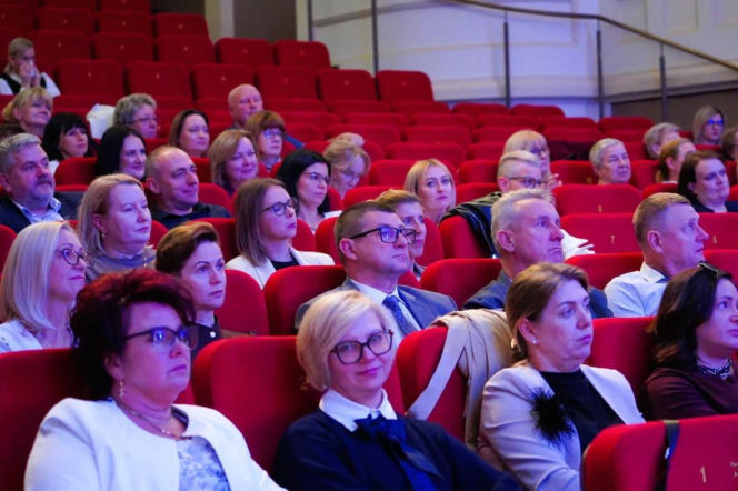 Publiczność siedząca w czerwonych fotelach kinoteatru podczas gali w Iławie. O nagrodach dla nauczycieli czytaj w Eska Iława.