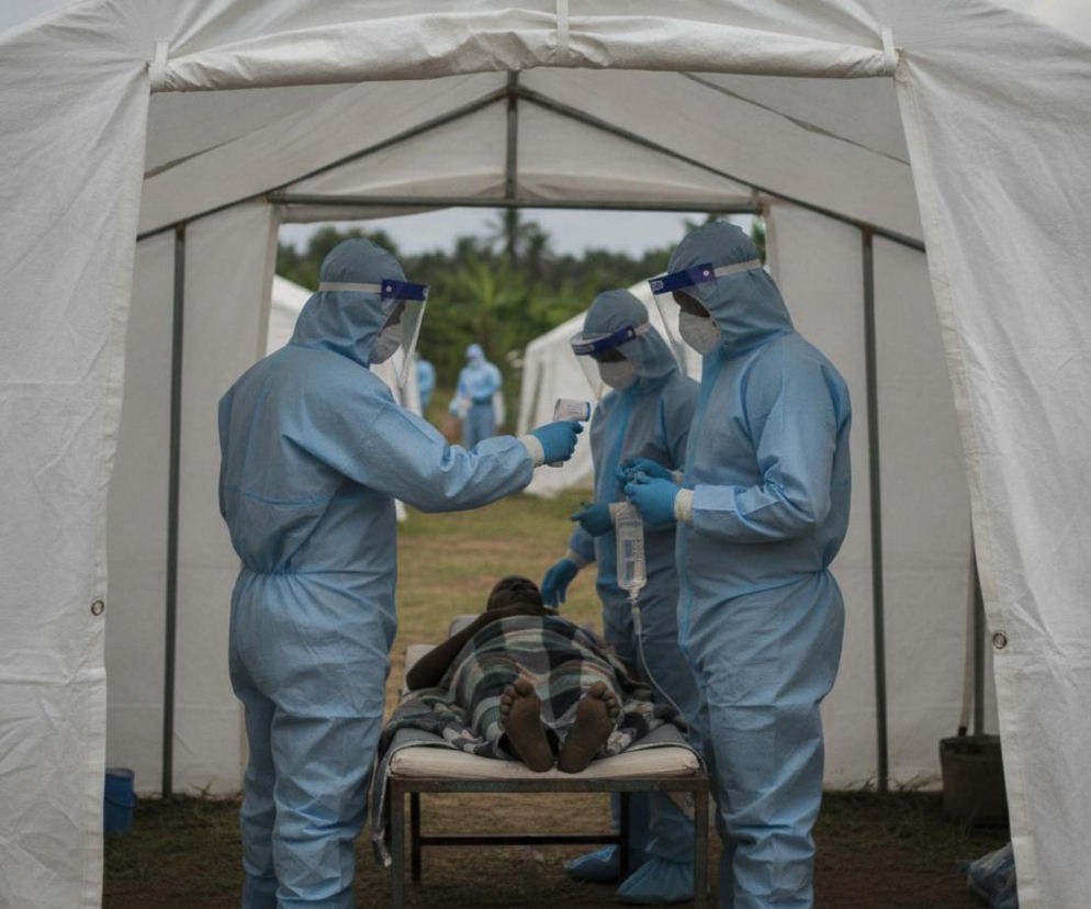 Medycy w kombinezonach pod namiotem badają pacjenta. O tragicznej epidemii Eboli w DRK przeczytasz na Poradnik Zdrowie.