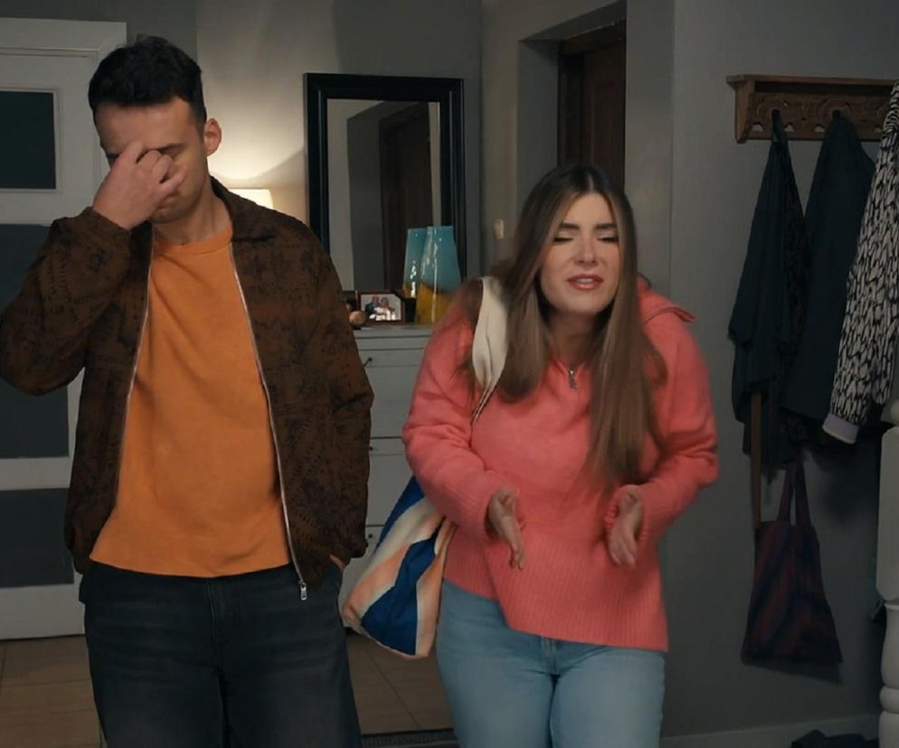 Agata (Natalia Zambrzycka) w różowym swetrze i jasnych jeansach stoi z miną niezadowolenia, a Ignacy (Olaf Staszkiewicz) w brązowej kurtce i pomarańczowej koszulce zakrywa twarz dłonią. Scena z odcinka serialu Barwy szczęścia dostępnego na platformie Super Seriale.