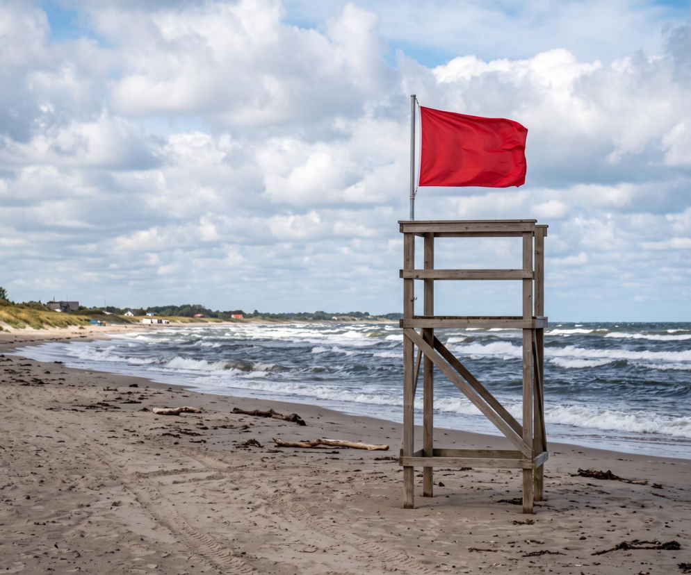 Czerwona flaga na wieży ratowniczej na pustej plaży w Dziwnowie. O zakazie kąpieli przeczytasz na SE Szczecin.