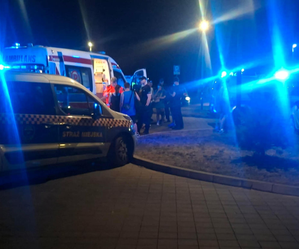 W nocy zdjęcie przedstawia karetkę pogotowia i pojazd Straży Miejskiej z włączonymi niebieskimi światłami, stojące przy grupie ludzi na chodniku, co nawiązuje do awantury nad Lubianką w Starachowicach, o której przeczytasz więcej na naszym portalu.