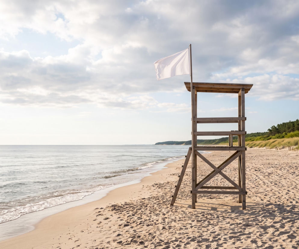 Drewniana wieża ratownicza z białą flagą na pustej plaży w Pobierowie. O pogodzie nad morzem czytaj w SE Szczecin.