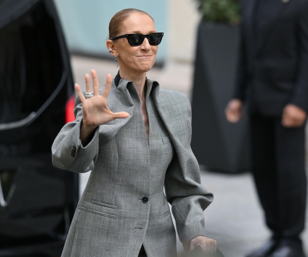 Céline Dion w szarym garniturze w kratę i okularach przeciwsłonecznych macha do fanów. O jej powrocie przeczytasz na Eska.