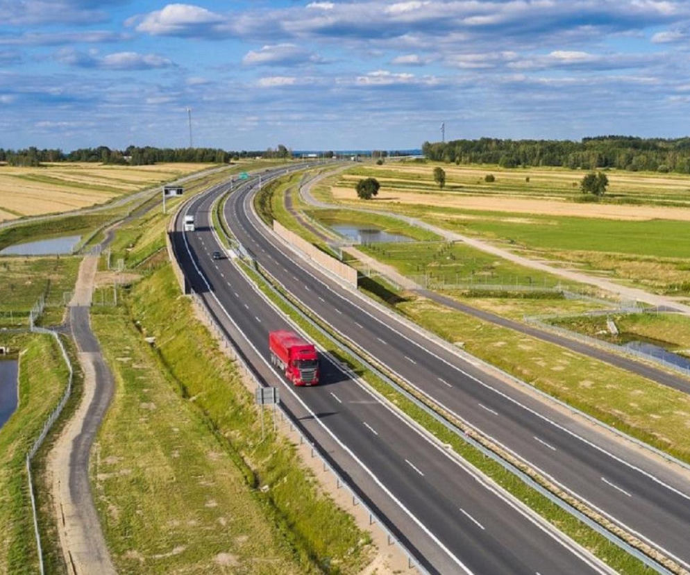 Droga ekspresowa z lotu ptaka pośród pól. Jedzie po niej czerwona ciężarówka. O trasie S74 przeczytasz na Eska Kielce.