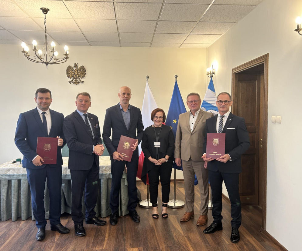 Grupa osób trzymających teczki z umowami w urzędzie. O inwestycji geotermalnej przeczytasz na Eska2.