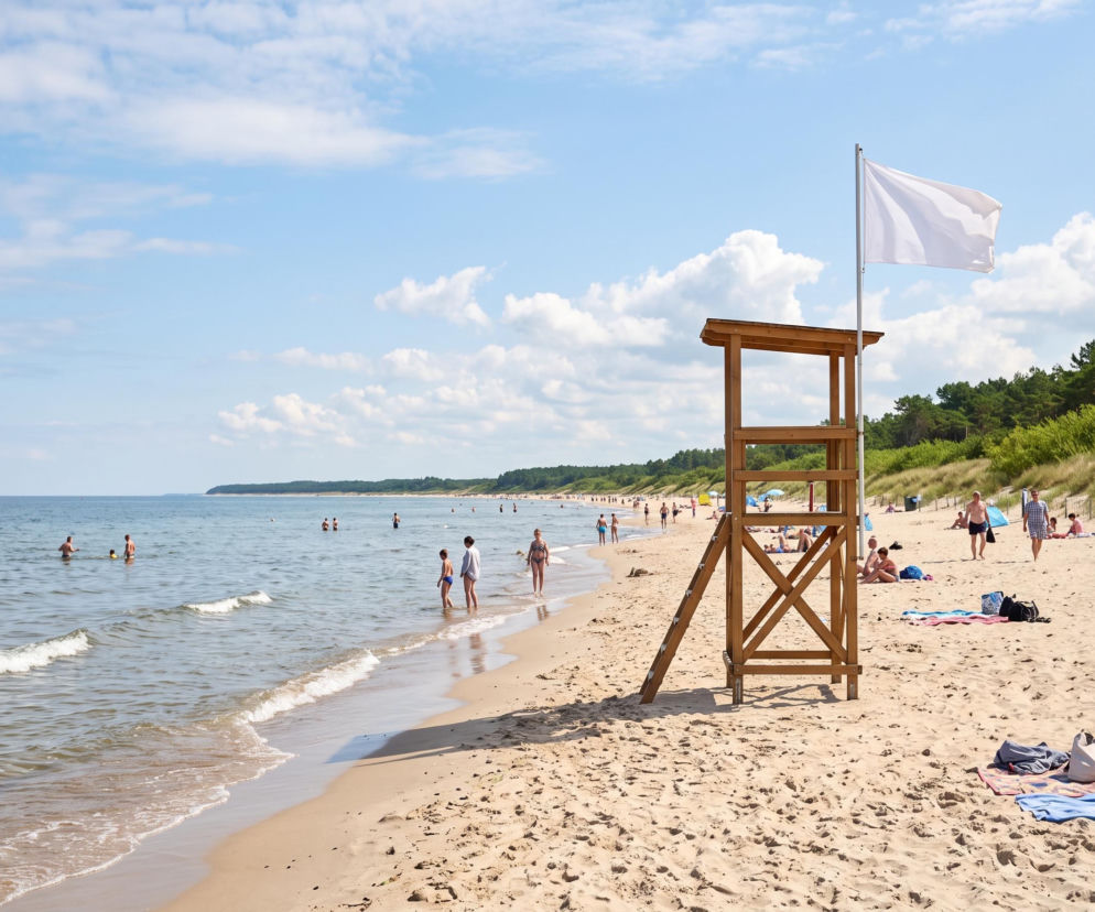 Plaża w Grzybowie z wieżą ratowniczą i białą flagą. O bezpieczeństwie nad morzem przeczytasz na SE Szczecin.