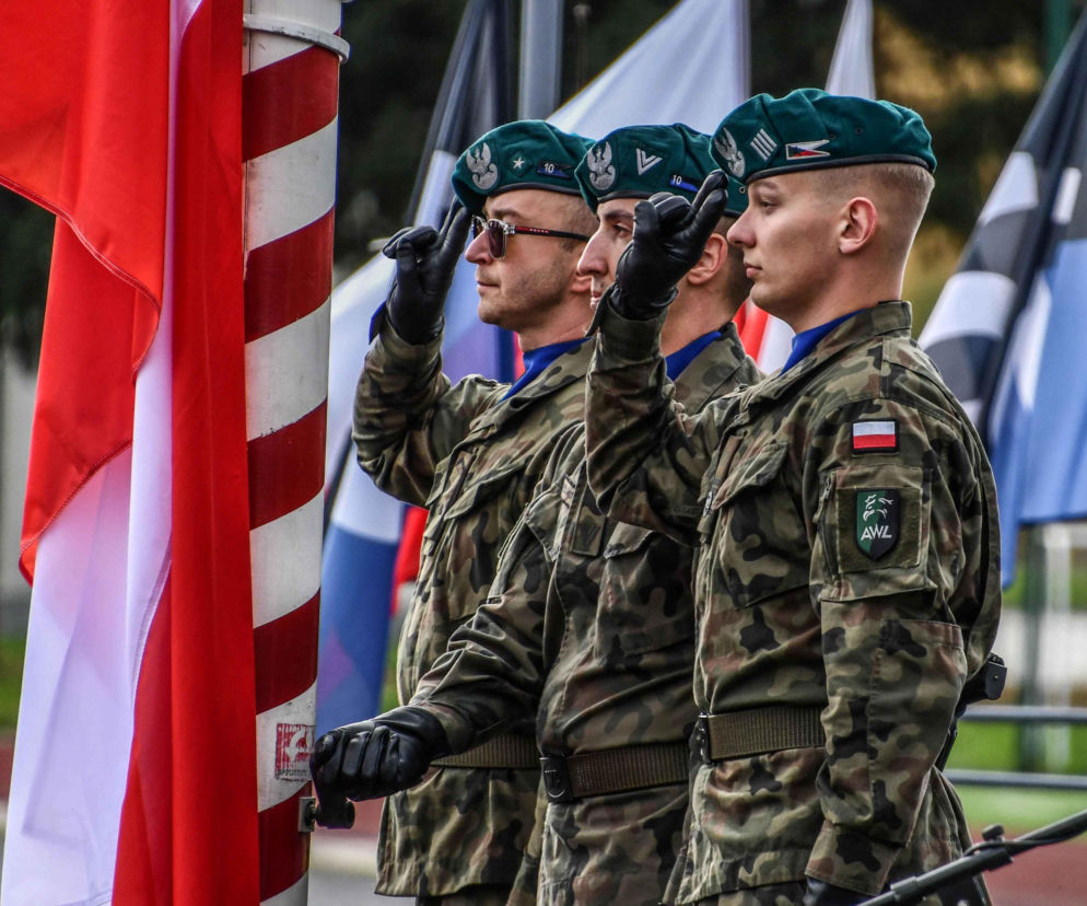 Trzej żołnierze w zielonych beretach salutują przy fladze Polski. O obchodach na SE Portal Obronny.
