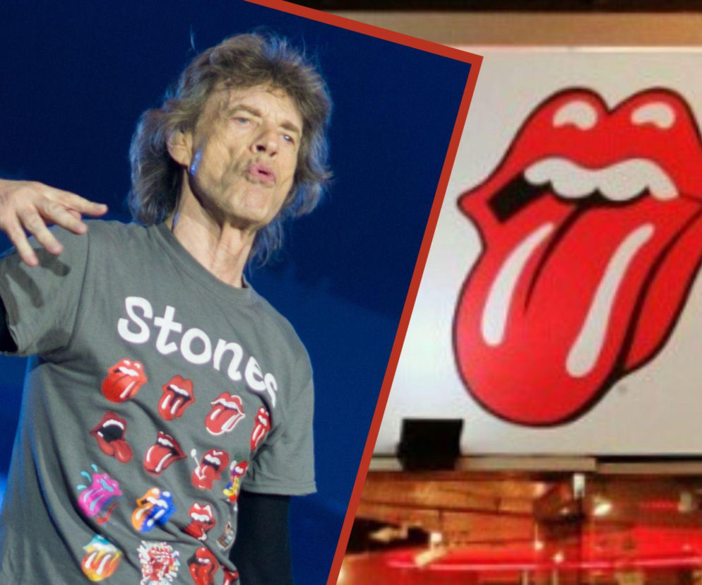 Mick Jagger w szarej koszulce z logo The Rolling Stones podczas koncertu, obok widoczne kultowe czerwone usta z językiem. Historia stworzenia tego symbolu buntu, zaprojektowanego przez Johna Pasche, to fascynujący temat, o którym przeczytasz więcej na naszym portalu.