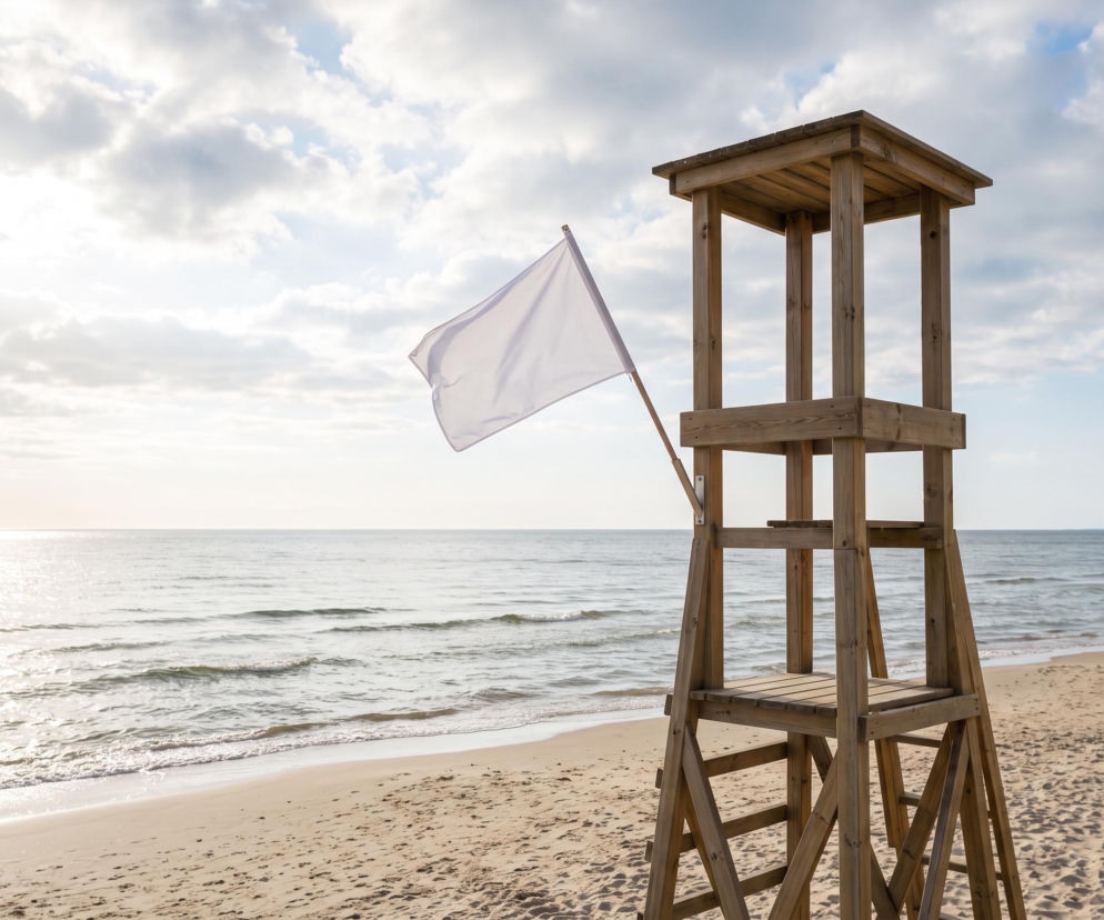 Drewniana wieża ratownika z białą flagą na plaży w Ustroniu Morskim. O bezpieczeństwie w wodzie przeczytasz w SE Szczecin.