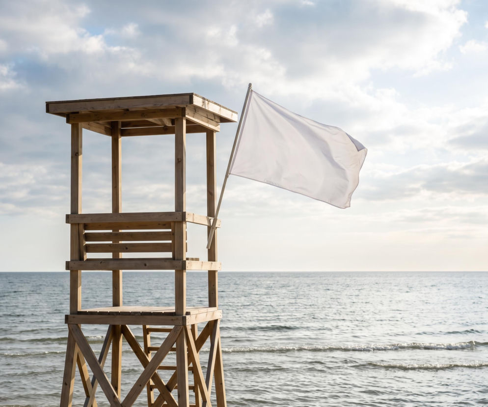 Drewniana wieża ratownicza z białą flagą na plaży w Sarbinowie. O bezpiecznej kąpieli przeczytasz na SE Szczecin.