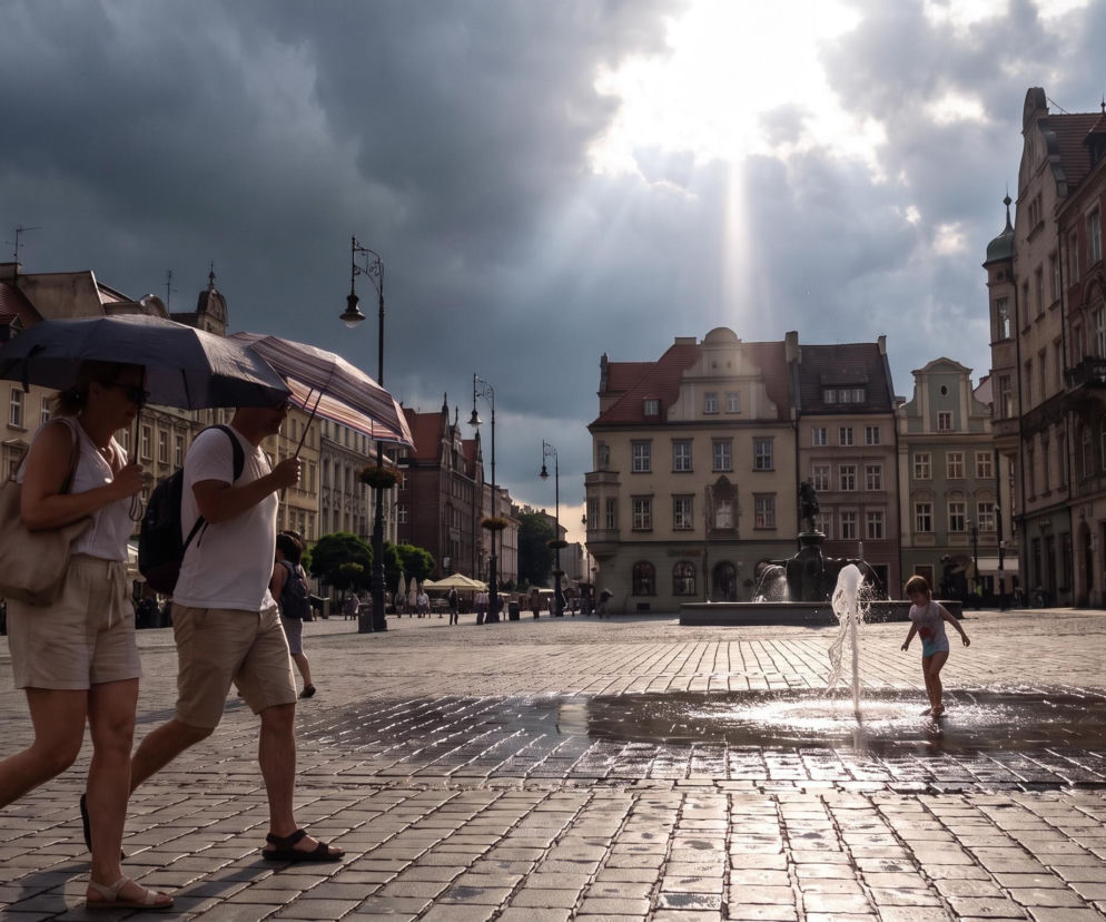 Para pod parasolami na rynku podczas słońca i ciemnych chmur. O pogodzie w Twoim regionie przeczytasz na Eska.