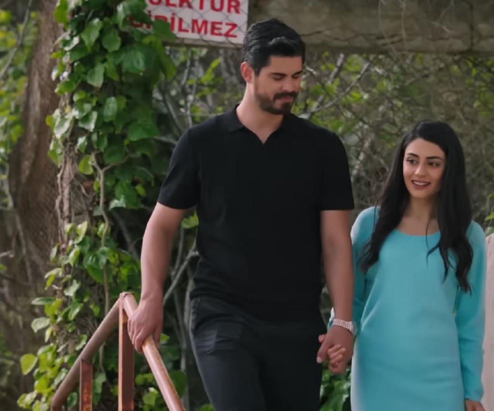 Hancer i Cihan trzymają się za ręce, uśmiechając się, idąc w otoczeniu zieleni, co symbolizuje rozkwitającą miłość po wspólnej nocy. Zdjęcie przedstawia romantyczne chwile bohaterów serialu Panna młoda z 77. odcinka, o których możesz przeczytać na Super Seriale.