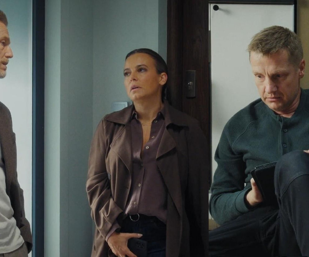 Trójka bohaterów serialu M jak miłość – Andrzej, Magda i Paweł – w scenie pełnej napięcia emocjonalnego. Magda (Anna Mucha) w brązowym płaszczu i koszuli, Andrzej (Krystian Wieczorek) w marynarce i białym T-shircie, oraz pogrążony w smutku Paweł (Rafał Mroczek) w ciemnozielonej bluzie, siedzący na podłodze z tabletem. Więcej o ich losach na stronie Super Seriale.