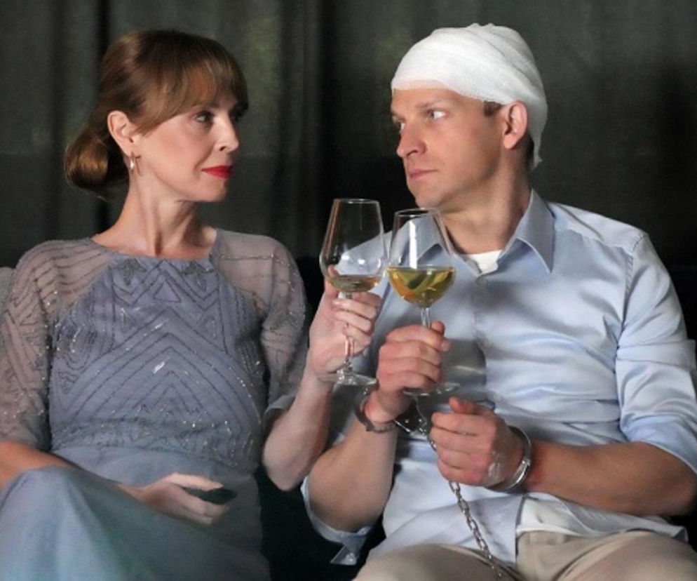 Katarzyna Tlałka jako Agnieszka i Michał Rolnicki jako Łukasz z serialu Barwy szczęścia w 3304 odcinku. Agnieszka w eleganckiej sukni i Łukasz z zabandażowaną głową, w kajdankach, trzymają kieliszki z winem. Więcej o ich losach na Super Seriale.