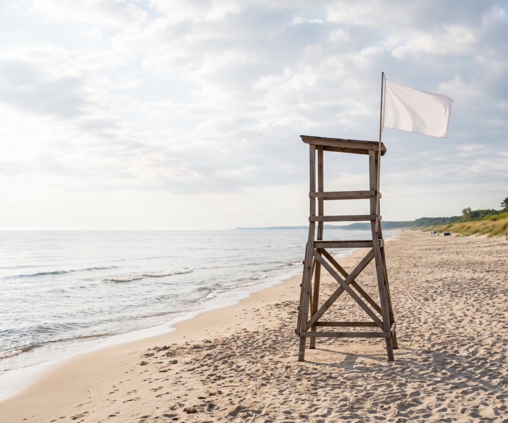 Drewniana wieża ratownicza z białą flagą na pustej plaży w Rewalu. O bezpieczeństwie nad morzem przeczytasz w SE Szczecin.