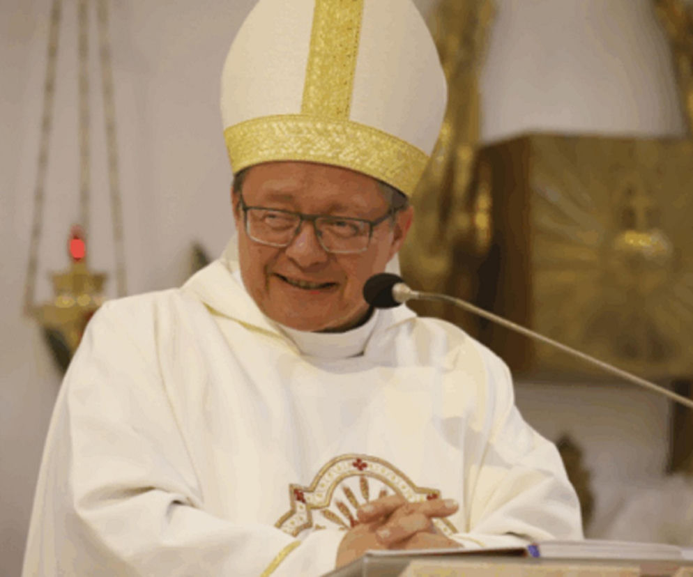 Kardynał Grzegorz Ryś w okularach, w białym ornacie i mitrze, uśmiecha się, przemawiając do mikrofonu podczas konsystorza. To zdjęcie ilustruje wydarzenia, o których więcej przeczytasz na naszym portalu.