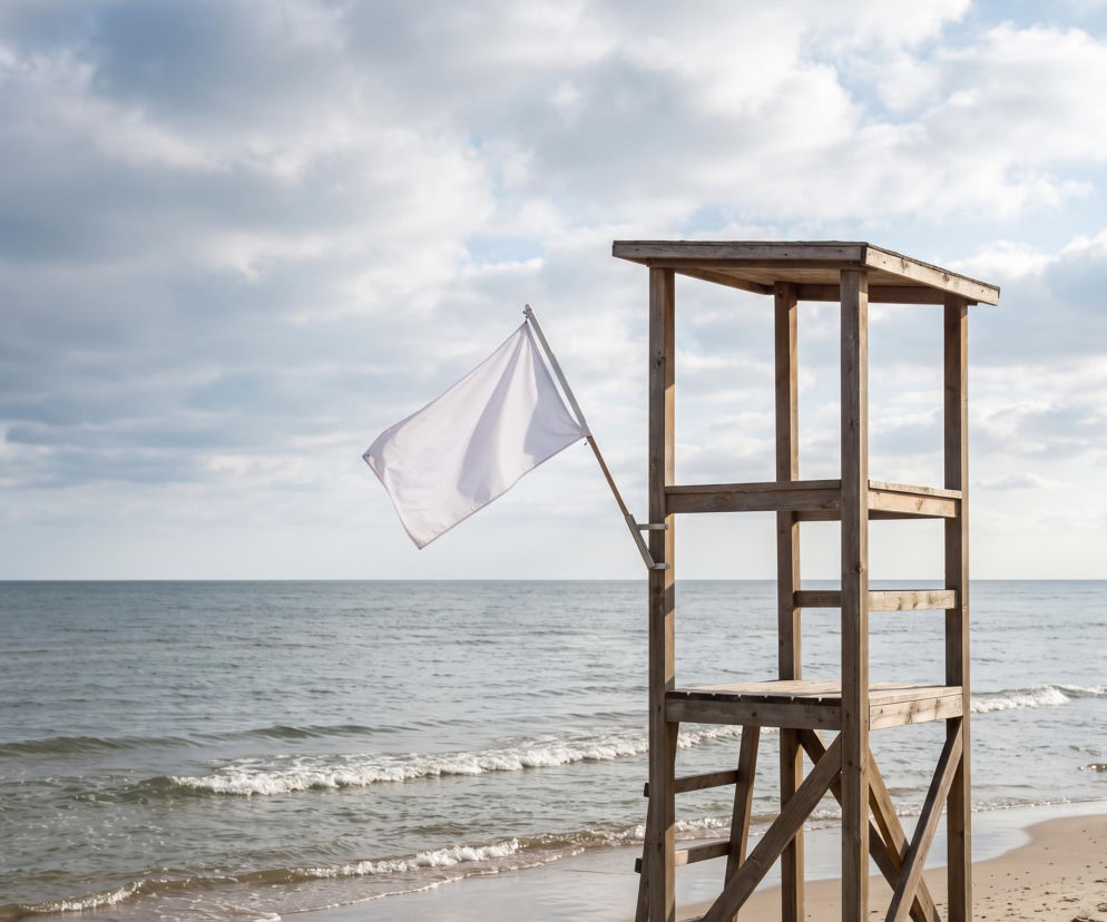 Biała flaga przy wieży ratowniczej na plaży w Dziwnowie. O braku sinic i czystej wodzie przeczytasz na SE Szczecin.