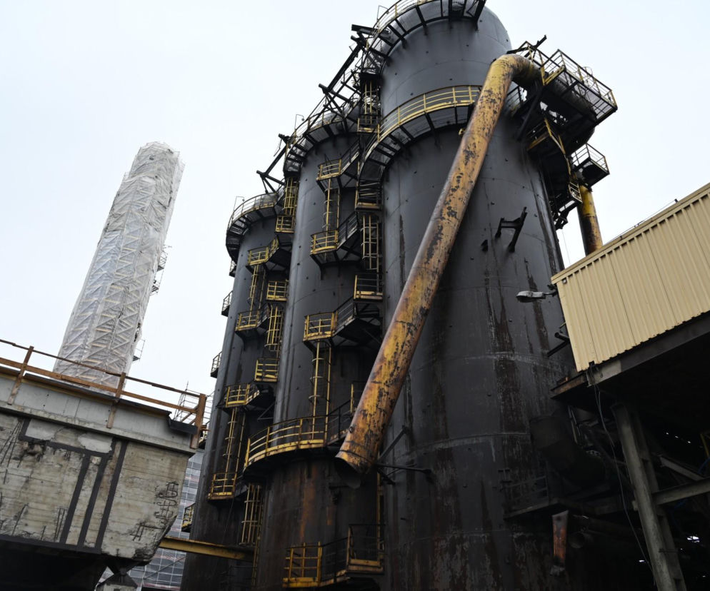 Wielki Piec Huty „Pokój” w Rudzie Śląskiej, z szarymi, metalowymi zbiornikami i żółtymi rurami, w tle widać betonowe konstrukcje i maszt w rusztowaniu. Obiekt przechodzi metamorfozę w Centrum Transformacji, o czym przeczytasz na Architektura Murator Plus.