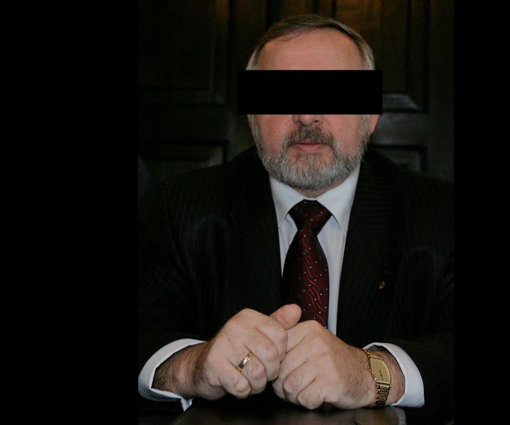 Mężczyzna w garniturze z czarnym paskiem na oczach. O zarzutach dla byłego posła Jana B. przeczytasz na SE Polityka.