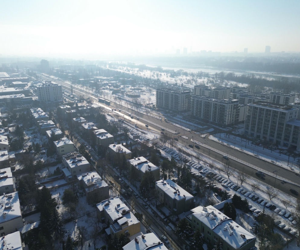 Zasypane śniegiem miasto, widok z lotu ptaka. Mglisty krajobraz z ulicami, budynkami i rzeką w tle symbolizuje problem smogu i jego wpływ na polską gospodarkę. Temat ten poruszany jest szeroko na portalu Super Biznes.