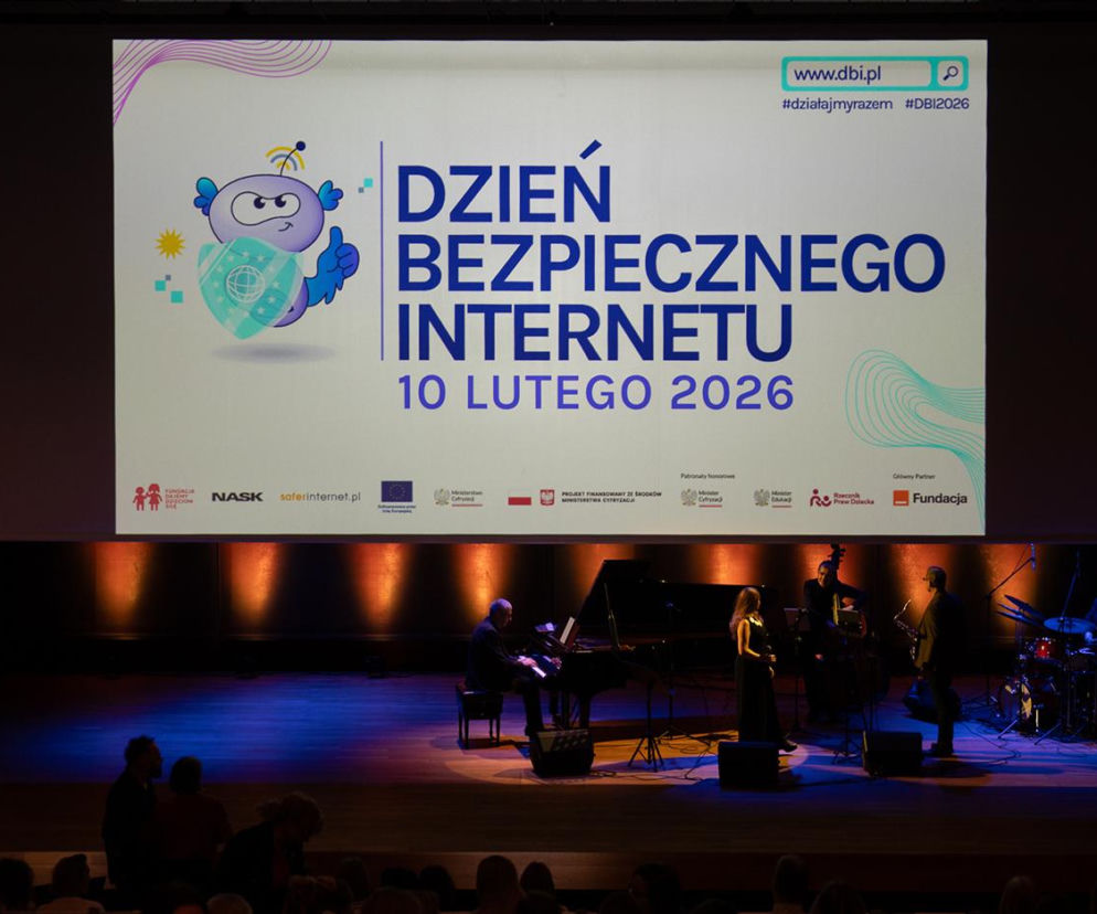 Scena muzyczna podczas Gali Dnia Bezpiecznego Internetu, z zespołem grającym na fortepianie, kontrabasie, saksofonie i perkusji, oraz wokalistką. Na ekranie widnieje grafika promująca Dzień Bezpiecznego Internetu 10 Lutego 2026. Więcej na ten temat na Super Biznes.