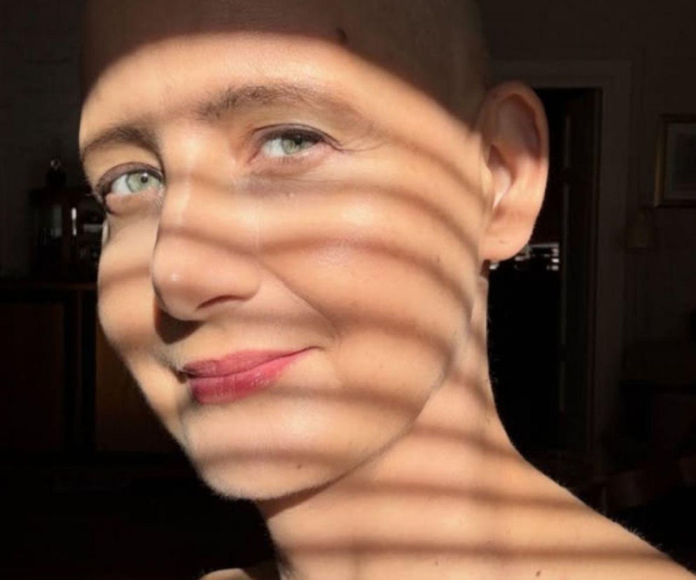 Aktorka Monika Pikuła uśmiecha się na tle pasów światła. O jej walce z nowotworem piersi przeczytasz na SE.