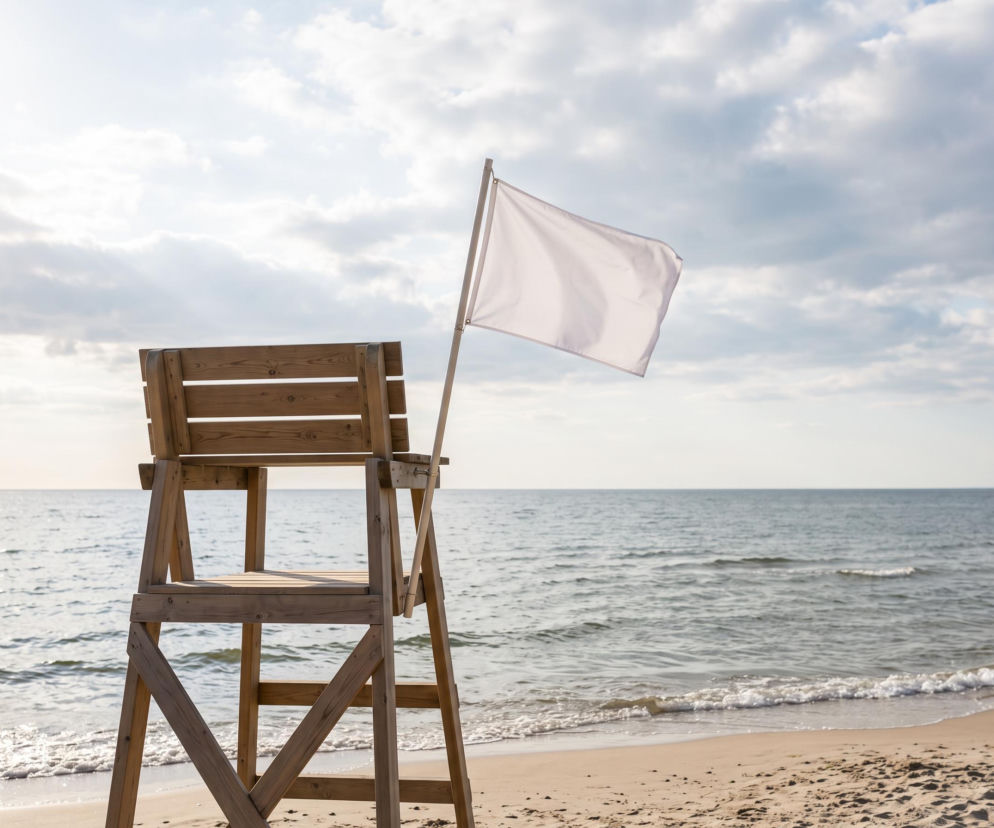 Biała flaga przy wieży ratowniczej na plaży w Darłowie. O bezpieczeństwie kąpieli przeczytasz na SE Szczecin.