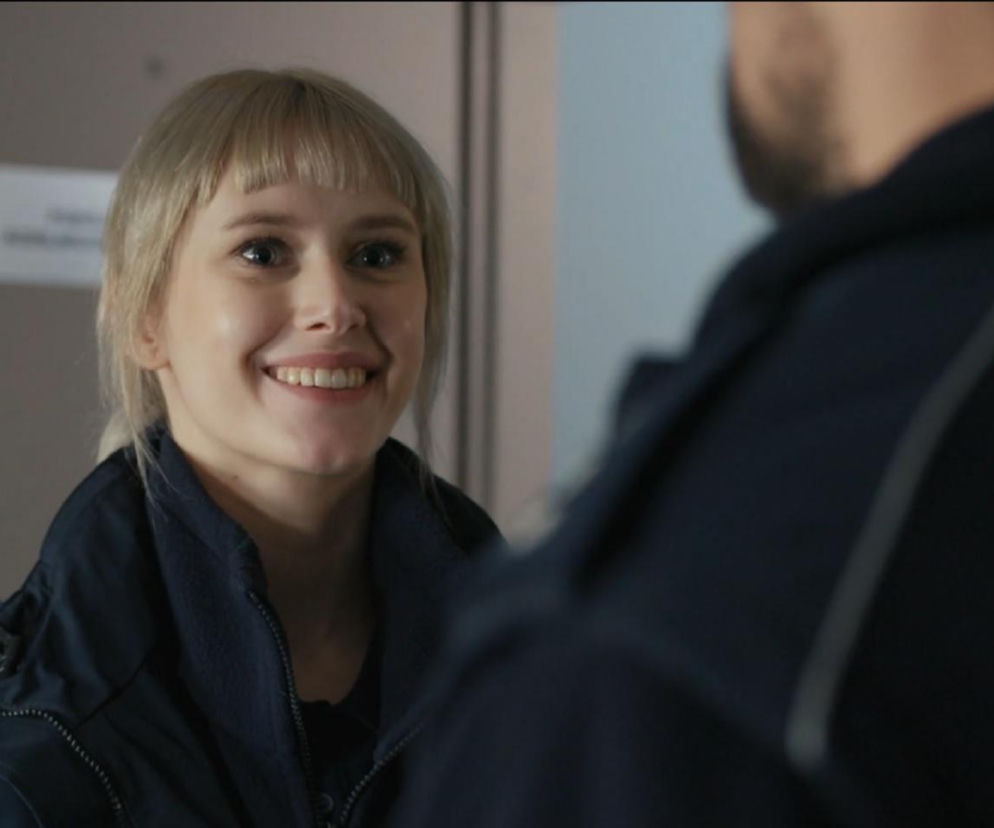 Uśmiechnięta blondynka w mundurze policji patrzy na kolegę z patrolu. O losach Darii i Marcina przeczytasz na Eska.