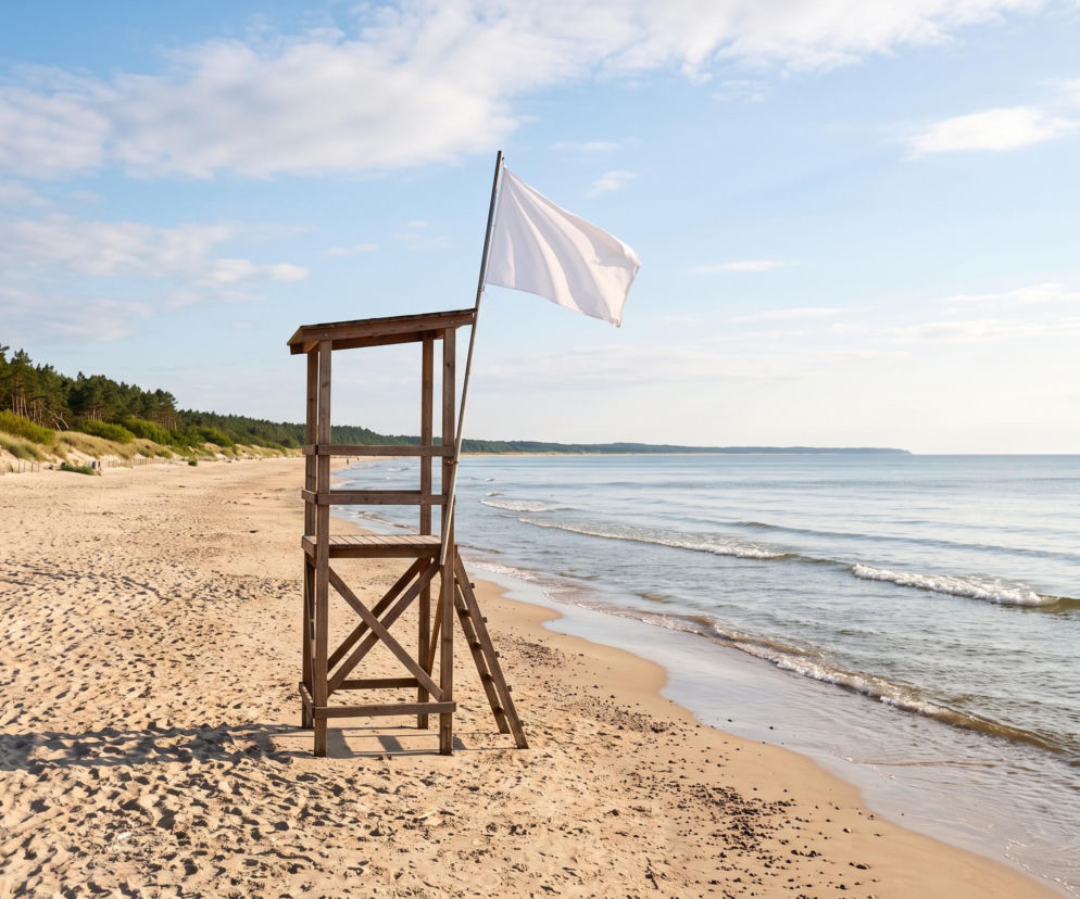 Drewniana wieża ratownika z białą flagą na pustej plaży w Łazach. O czystych kąpieliskach przeczytasz na SE Szczecin.
