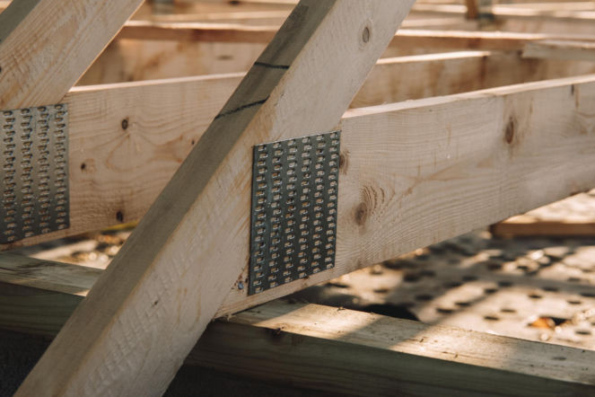 Detale więźby dachowej z drewnianymi belkami i łącznikami ciesielskimi.
