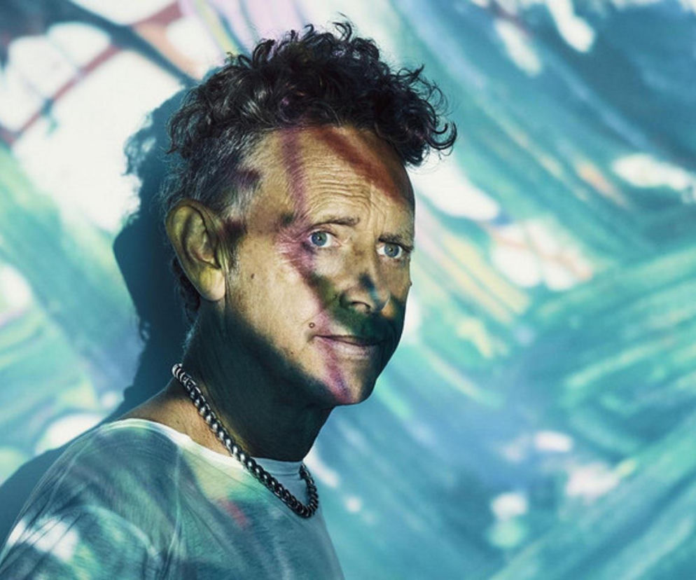Muzyk Martin Gore z Depeche Mode na tle kolorowych świateł. O tekstach zespołu przeczytasz na EskaRock.