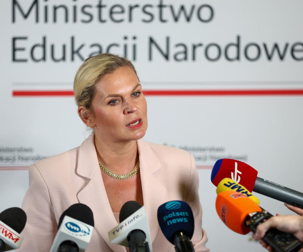 Minister Barbara Nowacka mówi do mikrofonów na tle logo resortu. O zmianach w szkołach przeczytasz na SE Polityka.