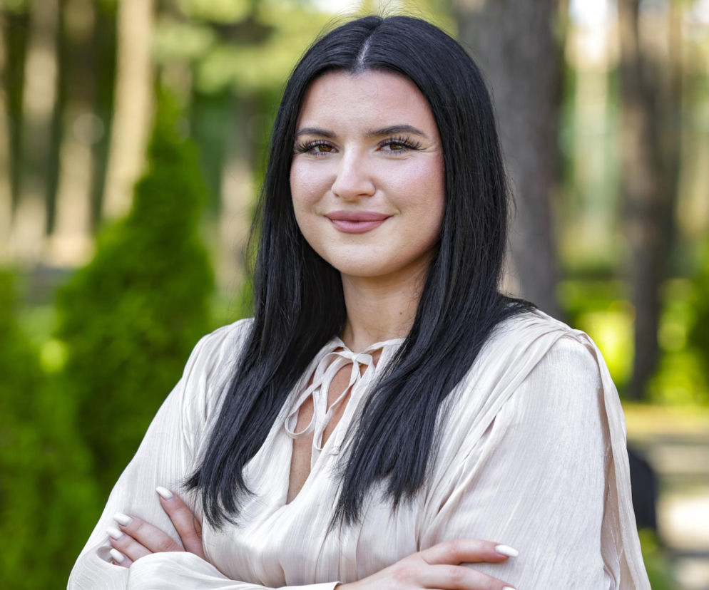 Justyna z programu Rolnik szuka żony uśmiecha się na tle zieleni. O uczestniczce show TVP przeczytasz na SE.