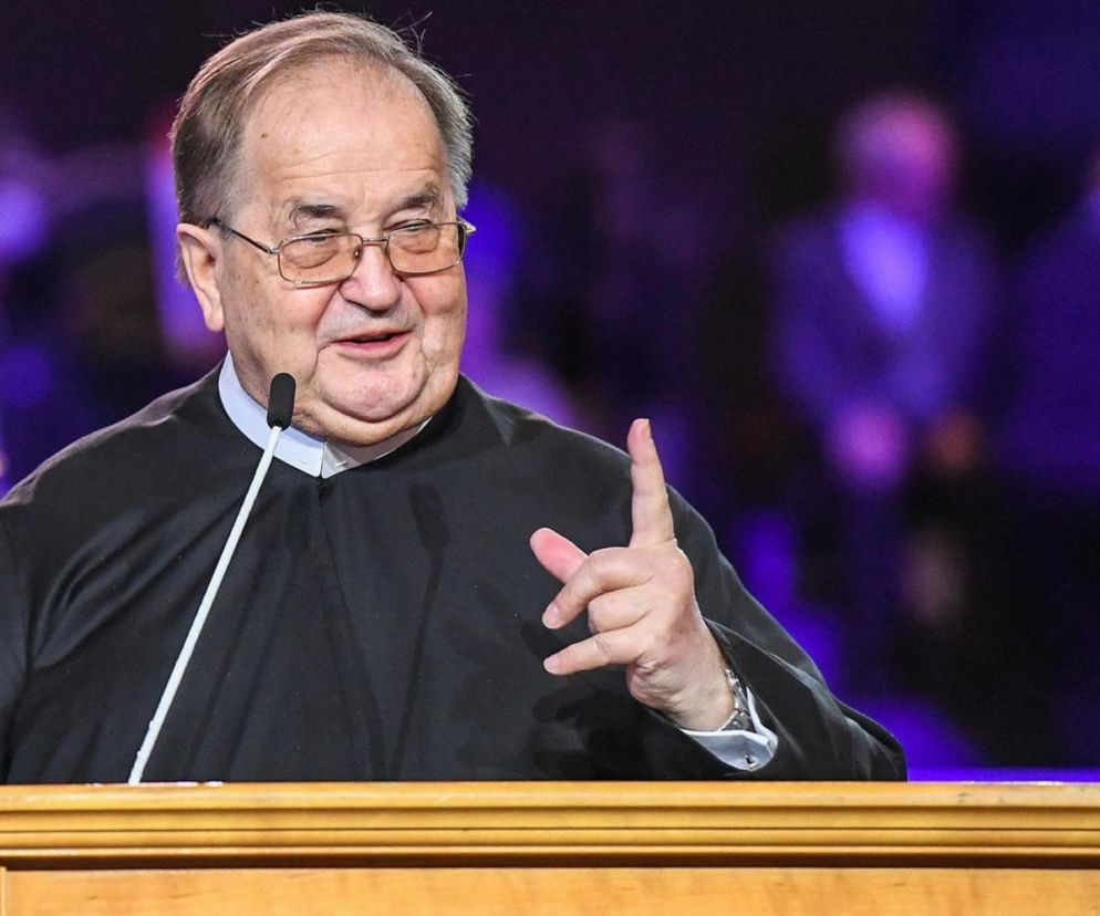 Uśmiechnięty ojciec Tadeusz Rydzyk przy mównicy. O sukcesie rekrutacji na jego uczelni przeczytasz na SE.