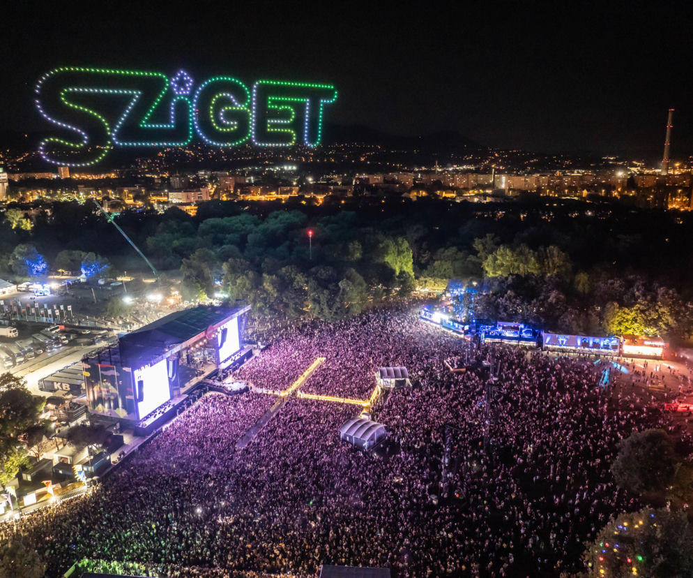 Tłum ludzi pod główną sceną Sziget Festival nocą. Nad wyspą świeci neonowy napis Sziget. O festiwalu przeczytasz w Eska.