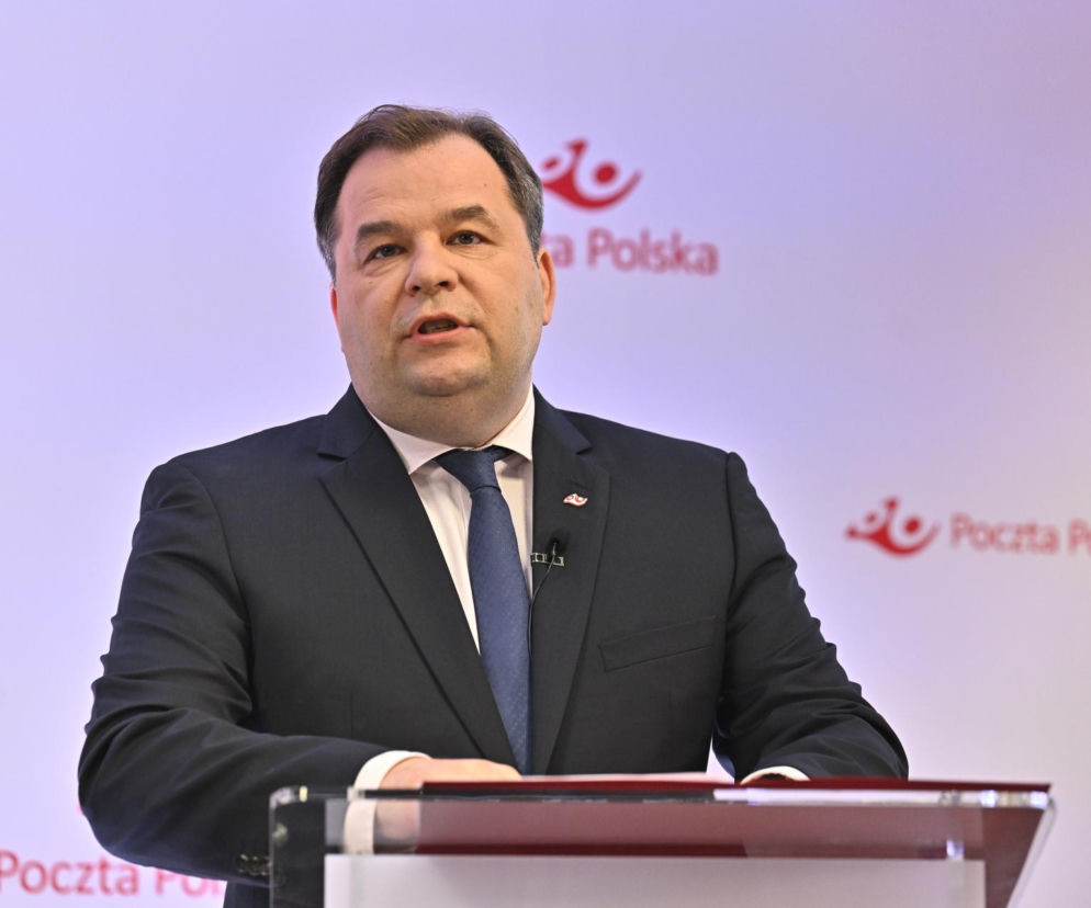 Sebastian Mikosz, odwołany prezes Poczty Polskiej, w ciemnym garniturze i krawacie, przemawia na konferencji prasowej, z logo Poczty Polskiej w tle. Wypowiedź Mikosza o dymisji można przeczytać na Super Biznes.