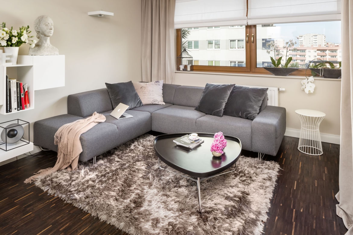 Szara sofa narożna w przytulnym salonie z kuchnią