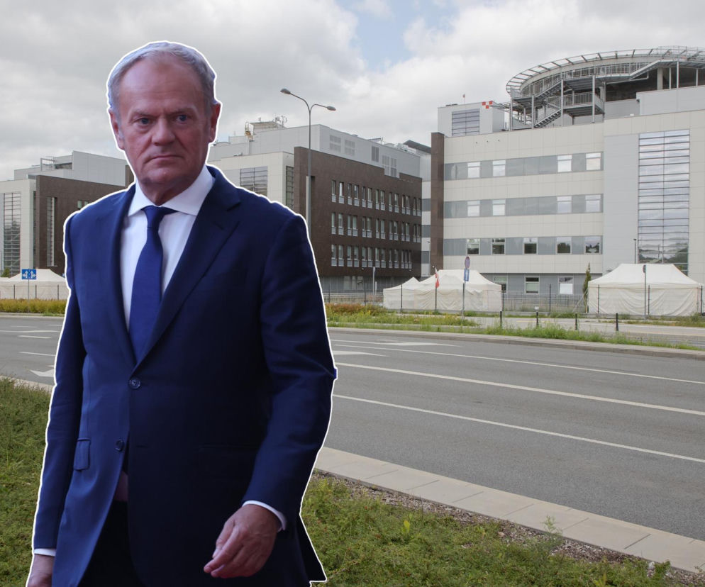 Donald Tusk w granatowym garniturze i krawacie, z poważną miną, na tle budynku Szpitala Południowego, symbolizującego aferę medyczną, o której można przeczytać więcej na naszym portalu. Obok budynku widać namioty i fragment ulicy.