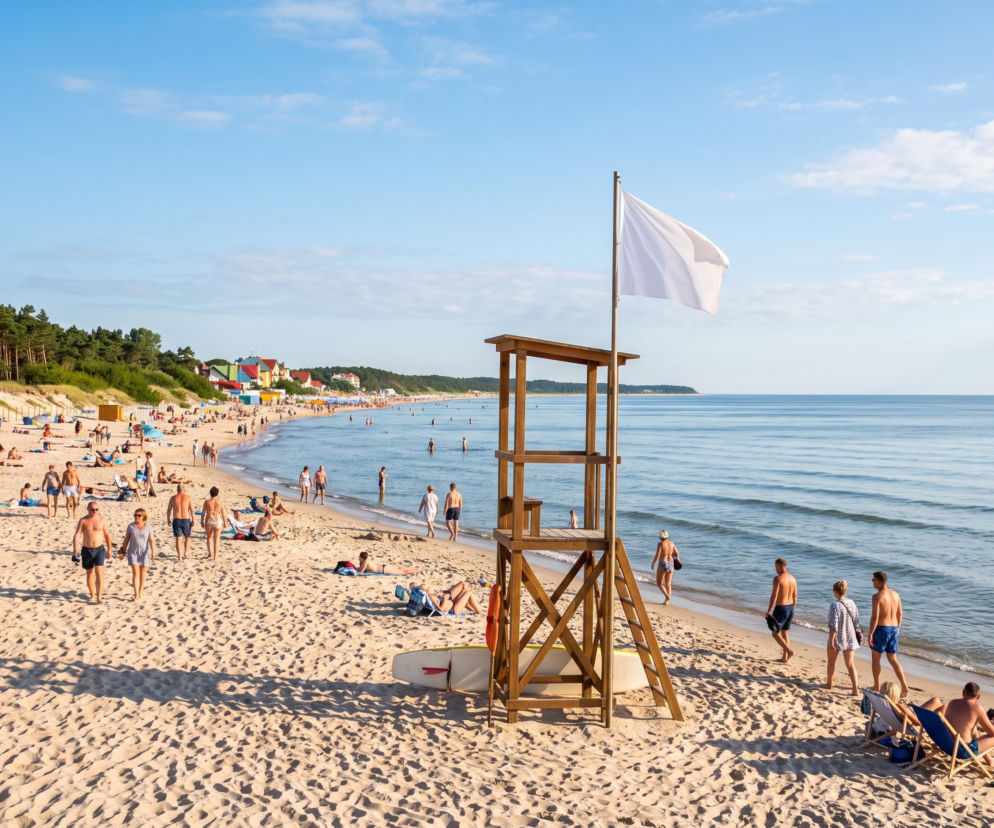Słoneczna plaża w Pobierowie z białą flagą na wieży ratowniczej. O warunkach nad morzem przeczytasz na SE Szczecin.