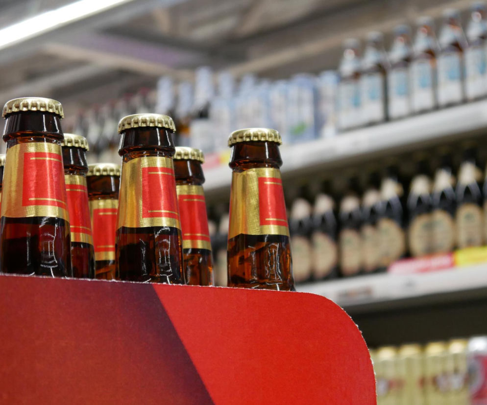Szklane butelki piwa na półce w sklepie. O wynikach sondażu dotyczącego nocnej prohibicji przeczytasz na Eska.