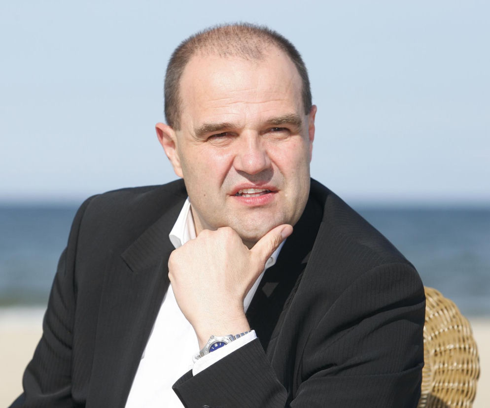 Aktor Cezary Żak oparty o dłoń na tle plaży. O fenomenie serialu Ranczo i radach aktora przeczytasz na Eska.